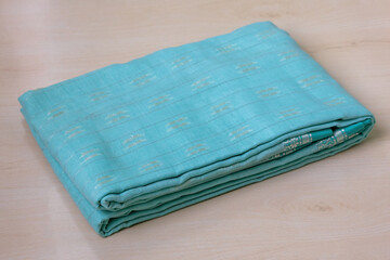 A folded cotton saree, displayed on a wooden surface. Sarees are a popular choice for Bangladeshi women, especially during weddings and festivals.