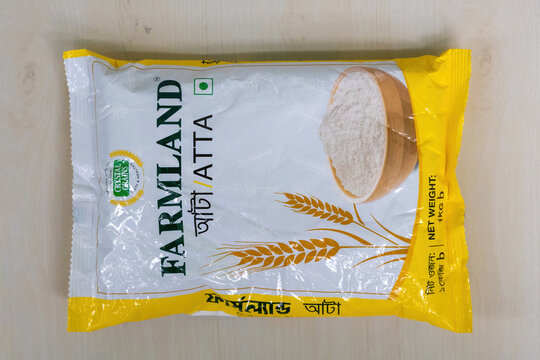 A packet of Farmland Atta wheat flour on a wooden background. Farmland Atta is a popular brand of wheat flour in Bangladesh.