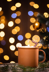 gingerbread man in a cup of cocoa with marshmallows on a Christmas background among New Year lights.