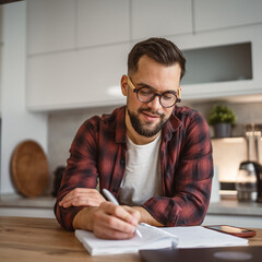 adult man write notes in a notebook and study at kitchen