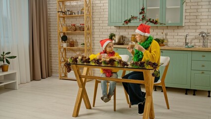Mother and daughter in the christmas decorated kitchen, mom teaching girl making gingerbread...