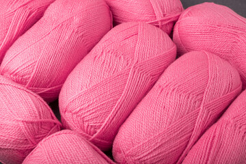 several skeins of bright pink acrylic yarn for crocheting or knitting. Flat lay close up shot, top view