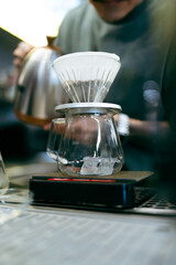 Professional barista making filtered drip coffee in coffee shop. Close up of hands barista brewing a drip hot espresso coffee, pour over coffee with hot water and filter paper in coffee cafe.