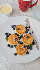 Tender cottage cheese pancakes with a golden crust, served with juicy blueberries. An ideal breakfast or dessert that combines the softness of syrniki with the freshness of berries.