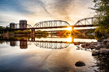 Naklejka premium A bridge spans a river with a sunset in the background