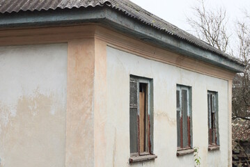 facade one white brown old  house with three windows under a gray slate roof on a rural street