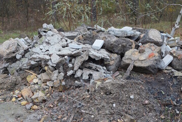 one big pile of garbage from broken gray pieces of concrete old stones and bricks lie on the ground on the autumn street