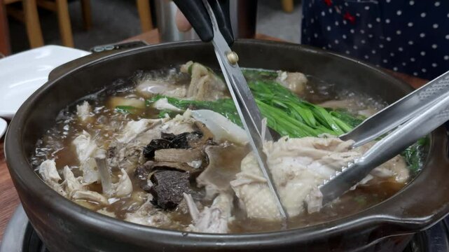 한국식 토종닭 버섯 백숙 요리에 부추를 다듬고 한바퀴 돌려주는 슬로우 모션 모습