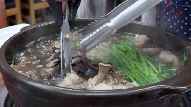 한국 전통 음식이다 엄청 크고 두꺼운 뚝배기 안에 토종닭과 버섯을 푹 삶은 뒤에 가위로 손질하는 모습