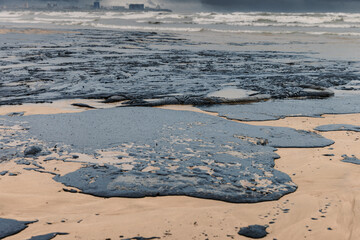 Oil leak in sea coastline after a tanker wreck. Fuel oil polluted beach