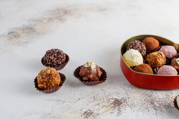 Homemade chocolate truffles with dark chocolate ganache covered with pink powder, waffle crumbles, gold flakes, coconut and nuts