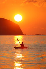 silhouette of a man in a canoe with a sunset background