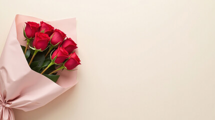 A bouquet of vibrant red roses wrapped in soft pink paper, placed on a beige background. Perfect for romantic or celebratory concepts. Flower delivery concept. Copy space