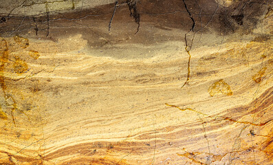 Layered sandstone texture in warm earthy tones with visible cracks and intricate patterns, showcasing the beauty of natural geological formations.