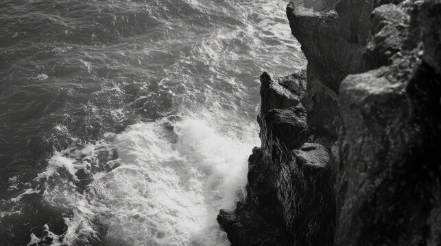 Rocky shoreline waves crashing against cliffs viewed from a historic lighthouse in dramatic black and white photography. - Powered by Adobe