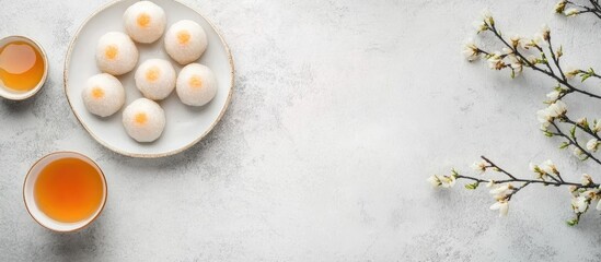 Sweet rice dumpling balls Tang Yuan on plate with tea and flowering branches overhead view for festive cuisine presentation