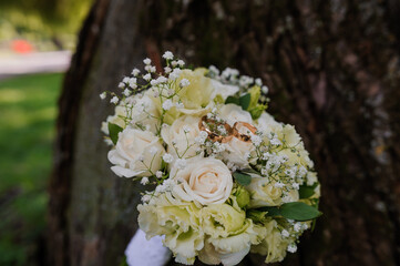 Beautiful Wedding Bouquet with White Roses and Wedding Rings Nestled Amongst Greenery