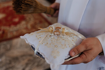 Elegant Wedding Rings Presented on Ornate White Cushion with Ceremony Decor