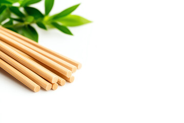 Obraz premium Set of bamboo chopsticks with green leaves on a white background.