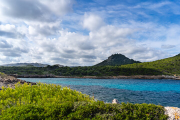  Cala Agulla, Mallorca, Spain, October 27, 2021 - Mountain peak rising above turquoise Mediterranean bay with pine forest