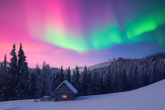 Small wooden cabin in snowy mountains under incredible Northern lights in starry sky. Christmas landscape with Polar lights in winter time. Aurora Borealis - Powered by Adobe