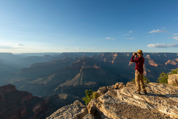 Guy looking at binoculars in hill. man in t-shirt with backpack. Young Caucasian man during hike in valley landscape