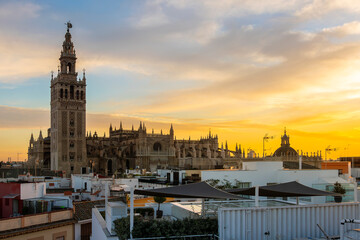 Obraz premium Sunset view from a rooftop overlooking the Andalusian city of Seville, Spain, with the Giralda Tower and the great Seville Cathedral in view over the skyline. 