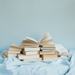 Open book on a pile of books on a bed.