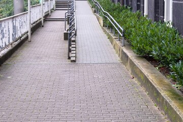 Wheelchair ramp and stairs providing accessibility with metal railings and green shrubs