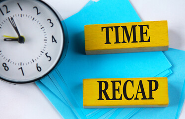 TIME RECAP - words on yellow wooden blocks on a clock background