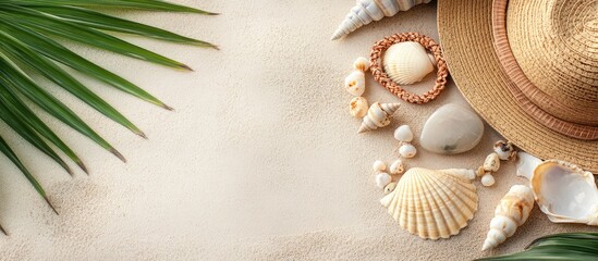 Tropical beach accessories arrangement featuring a hat, seashells, and natural stones on sandy surface with empty space for text design