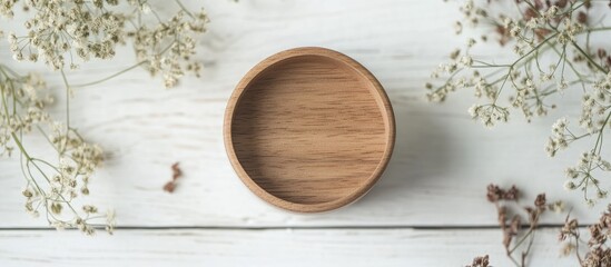 Fototapeta premium Wooden ring jar on a white wooden table surrounded by dried flowers creating a minimalist staged product photography composition