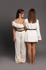Portrait of beautiful twin sisters on grey background