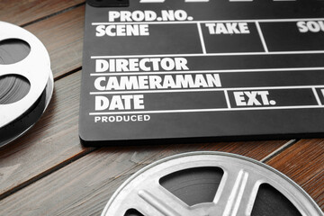 Movie clapper and film reels on wooden table, closeup