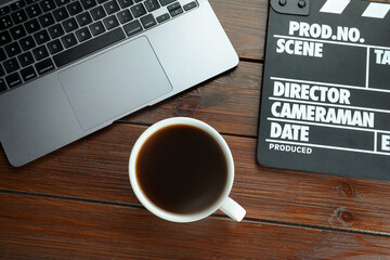 Movie clapper, laptop and coffee on wooden table, flat lay