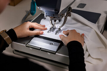 Woman working with sewing machine in professional workshop, closeup