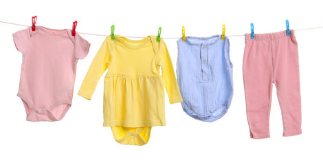 Different baby clothes drying on laundry line against white background