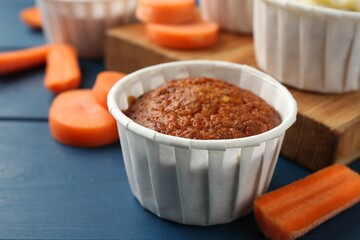 Delicious carrot muffins and fresh vegetables on blue wooden table, closeup