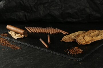 Tobacco, dried leaves, cigarettes and cigar on black table