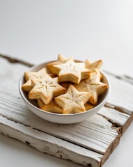 Star shape biscuits in a bowl on a white wooden planks