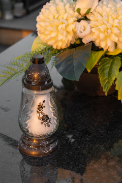 Candle and yellow chrysanthemums on the grave.