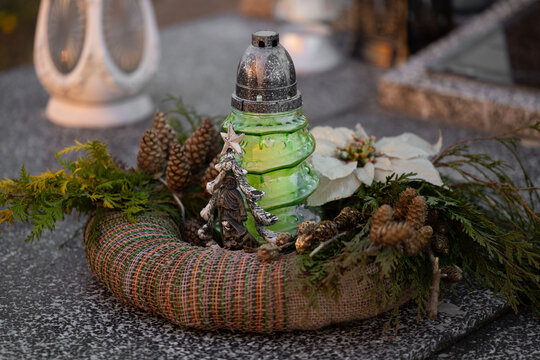 Christmas decoration on a grave: a wreath and a candle in the shape of a Christmas tree.