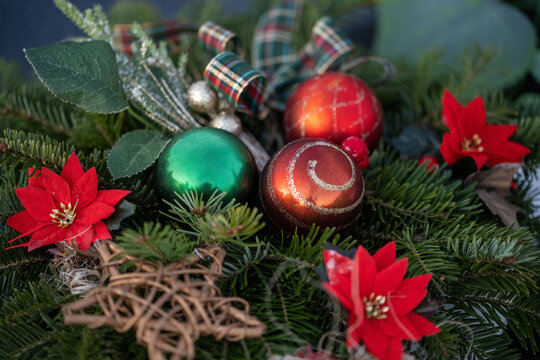 Christmas decoration of spruce branches, baubles and poinsettia flowers.
