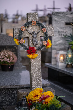 A cross on a grave decorated with a floral wreath.