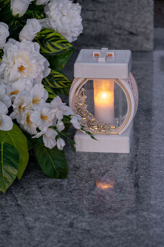 Elegant white flowers and a white candle on the grave.