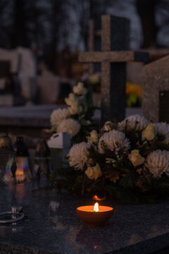 Candle and flowers on a grave at night.