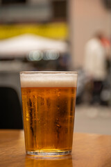glass of craft beer on restaurant table in city center on wooden table close-up