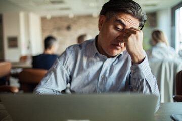 Stressed businessman working on laptop in office setting