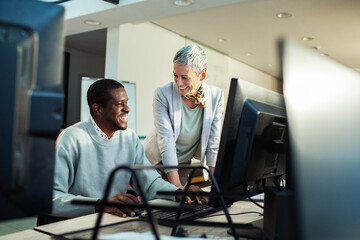 Team collaboration at office desk with dual monitors and brainstorming