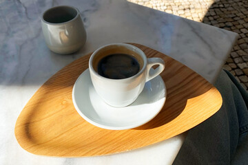 Coffee in a white cup on a wooden plate on a table